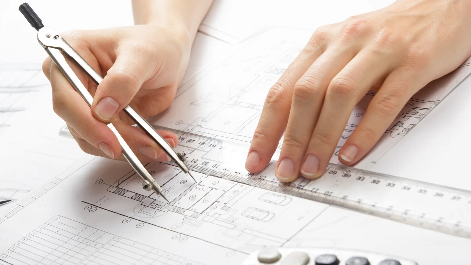 Designer drawing cabinetry shop drawings with a compass and scale ruler